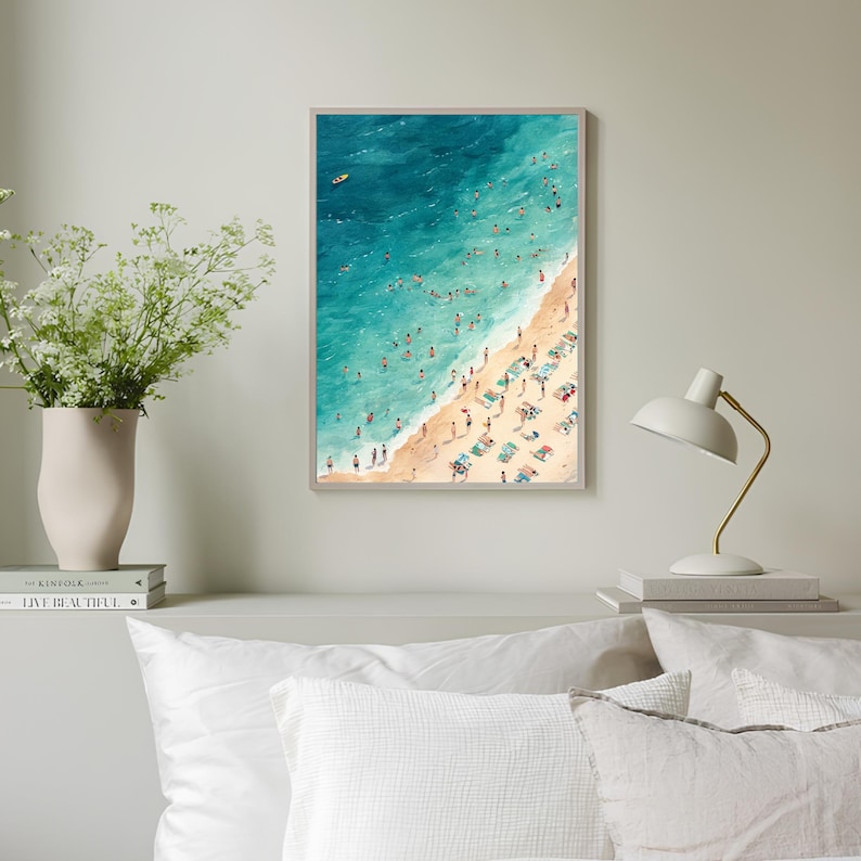 May include: An aerial view of a beach scene with turquoise water and a sandy shore. People are swimming, sunbathing, and relaxing on beach chairs. A small yellow boat is visible in the distance.