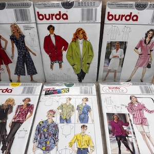 Puede incluir: Una colección de sobres de patrones de costura Burda. Los sobres presentan ilustraciones de varias prendas, incluyendo vestidos, monos y chaquetas. Los patrones están etiquetados con números y los logotipos de Burda Studio y Couture.