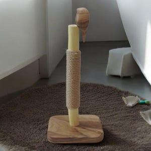 May include: A wooden cat scratching post with a natural rope covering and a wooden bird on top. The post is on a brown rug.