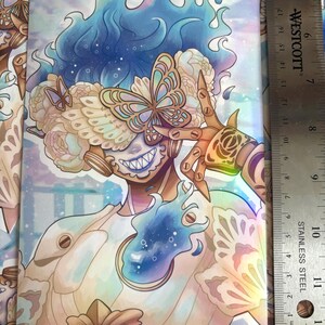 Pode incluir: Uma impress&atilde;o retangular com um personagem estilizado de cabelo azul, m&aacute;scara de borboleta e m&atilde;os mec&acirc;nicas. O personagem usa detalhes florais e uma pe&ccedil;a peitoral azul brilhante. Uma r&eacute;gua de a&ccedil;o inoxid&aacute;vel mede 43,18 cm.