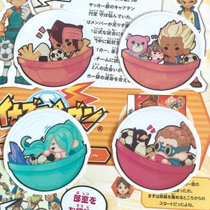 May include: Four round stickers featuring characters from the Inazuma Eleven anime series. Each sticker features a character in a soccer ball-shaped container. The characters are a boy with brown hair and a red headband, a girl with blue hair, a boy with blonde hair, and a boy with brown hair wearing goggles. The stickers are white with a red border and a lightning bolt design.