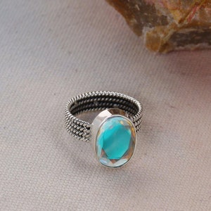 May include: A silver ring with a braided band and a large oval turquoise gemstone.