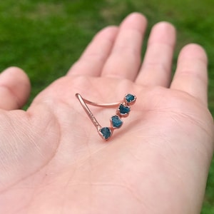 May include: A copper ring with five raw blue-green gemstones set in a curved shape.