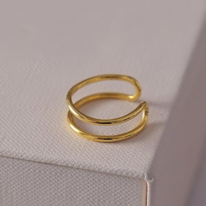 May include: A gold double-hoop ear cuff. The cuff is made of two thin hoops that are connected together.