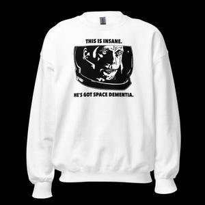 Op de afbeelding: Witte trui met een zwart-witte illustratie van een astronaut met de tekst "This is insane. He's got space dementia."