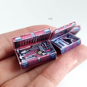 Peut inclure: Miniatures de boîtes à outils ouvertes, présentant de minuscules outils. Les boîtes à outils sont rouge foncé avec des accents argentés. Les outils à l'intérieur sont argentés et rouges. L'échelle est de 1:12.