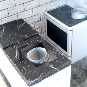 A digital printable template for a 1:12 scale dollhouse mini kitchen sink, designed for BMM system dollhouse setups. The template features a detailed, modern kitchen sink with a sleek faucet, ready to be printed on regular paper, cut, and assembled for a miniature kitchen scene.
