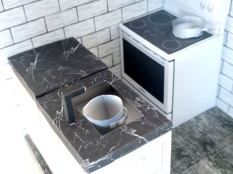 A digital printable template for a 1:12 scale dollhouse mini kitchen sink, designed for BMM system dollhouse setups. The template features a detailed, modern kitchen sink with a sleek faucet, ready to be printed on regular paper, cut, and assembled for a miniature kitchen scene.