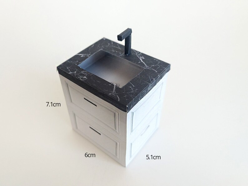 A digital printable template for a 1:12 scale dollhouse mini kitchen sink, designed for BMM system dollhouse setups. The template features a detailed, modern kitchen sink with a sleek faucet, ready to be printed on regular paper, cut, and assembled for a miniature kitchen scene.