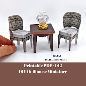 May include: Miniature dollhouse furniture set featuring two chairs, a small table, and a decorative lamp. The chairs and table have a dark brown finish with patterned fabric. The lamp has a clear glass shade and a gold base.