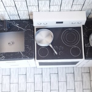 A digital printable template for a 1:12 scale dollhouse mini kitchen sink, designed for BMM system dollhouse setups. The template features a detailed, modern kitchen sink with a sleek faucet, ready to be printed on regular paper, cut, and assembled for a miniature kitchen scene.