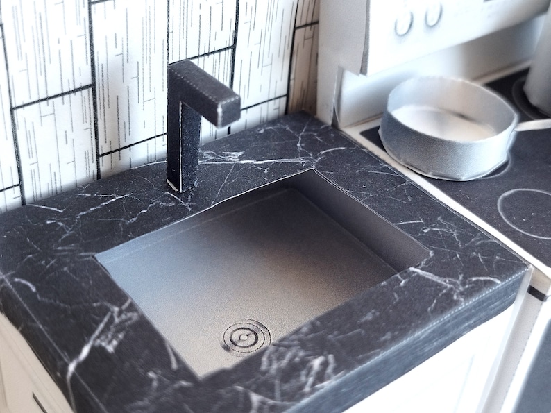 A digital printable template for a 1:12 scale dollhouse mini kitchen sink, designed for BMM system dollhouse setups. The template features a detailed, modern kitchen sink with a sleek faucet, ready to be printed on regular paper, cut, and assembled for a miniature kitchen scene.