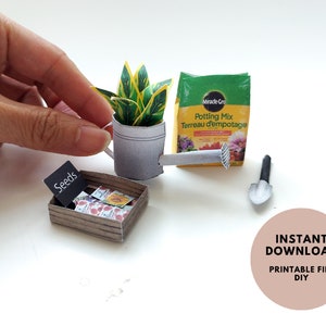 Puede incluir: Un conjunto de jardinería en miniatura de papel con una planta verde en una regadera, una bolsa de tierra para macetas, una pala pequeña y una caja de semillas. El conjunto está etiquetado como "Descarga instantánea Archivo imprimible DIY".