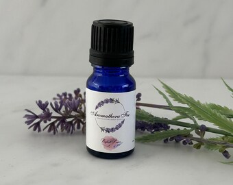 May include: A small cobalt blue glass bottle with a black screw-top cap and a white label. The label features a circular lavender wreath graphic, the text Aromathera Fee, and the text Perfect Peace with a small pink floral watercolour accent.
