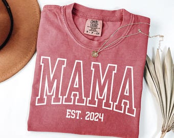 May include: A red t-shirt with the word "MAMA" in white outlined letters and the text "EST. 2024" below.