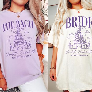two women wearing t-shirts with the same design, featuring a castle and the text "THE BACH" and "Scarflet's Bachelorette Miami, Florida".