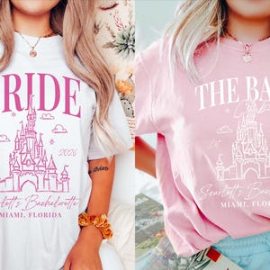 two women wearing t-shirts with the same design, which appears to be a castle or palace-themed design. The t-shirts are pink and white in color, and both women are wearing bracelets.