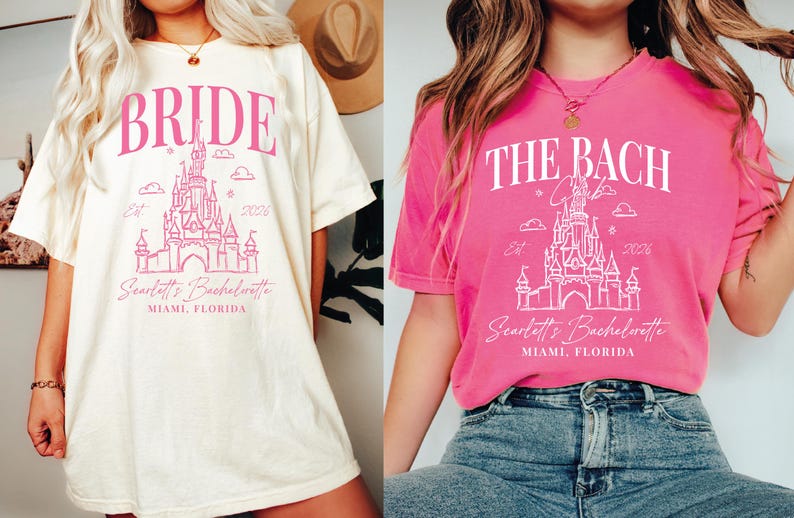 two women wearing t-shirts with the same design, which appears to be a wedding-themed graphic. The t-shirts are pink and white in color, and they both have the text "BRIDE" and "THE BACH" printed on them. The women are posing in front of a white wall, and they are wearing jeans and a hat.