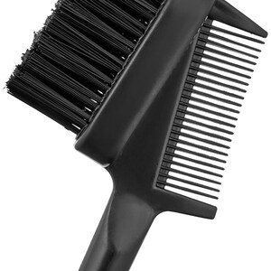 May include: A black dual-purpose grooming tool featuring a dense, rectangular brush head with stiff bristles on one side and a fine-toothed comb extending from the opposite side, connected by a solid black handle.