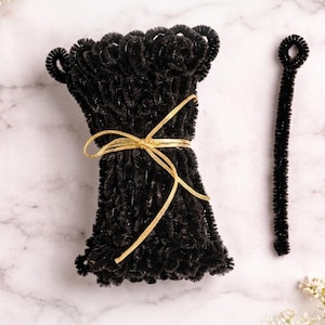 Puede incluir: Un conjunto de herramientas negras para peinar el cabello atadas con una cinta dorada, con una sola herramienta a la derecha. El texto "No Prep Needed" y "Better Hold • Defined Curls" también es visible.