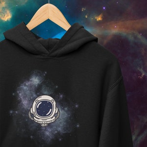 May include: Black hoodie with a white astronaut helmet graphic against a blue and purple galaxy background.