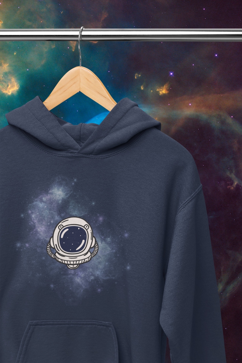 May include: A navy blue hoodie with a white astronaut helmet graphic against a galaxy background.