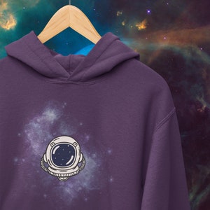 May include: Purple hoodie with a white astronaut graphic on a galaxy background.