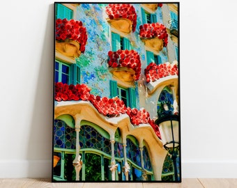 Può includere: Stampa incorniciata di una facciata di un edificio con balconi ornati traboccanti di fiori rossi. L'edificio ha un esterno strutturato blu chiaro e bianco, persiane turchesi e finestre ad arco. Una cornice nera circonda l'opera d'arte.