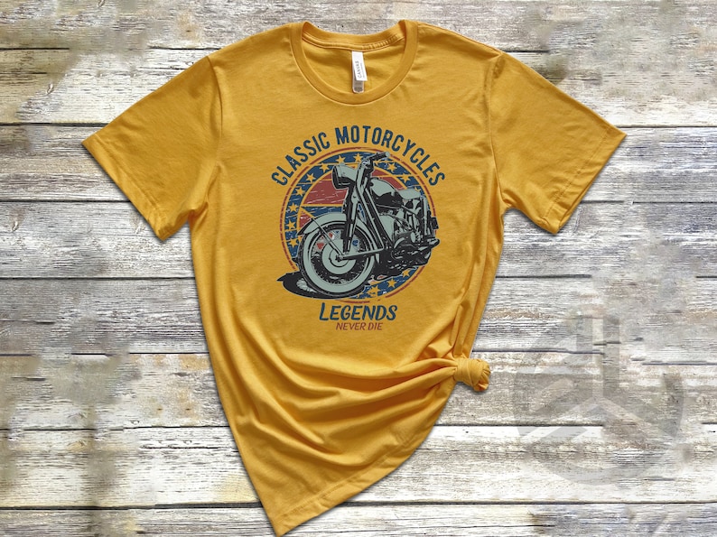 Op de afbeelding: Een geel T-shirt met een vintage-stijl grafische afbeelding van een motorfiets. De afbeelding bevindt zich in een cirkel met de tekst "Classic Motorcycles" en "Legends Never Die".