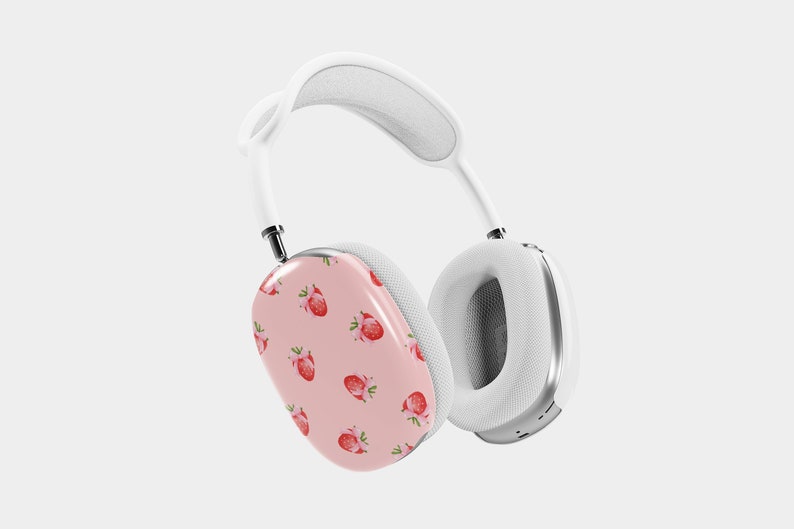 Puede incluir: Auriculares inal&aacute;mbricos blancos con una almohadilla rosa con un patr&oacute;n de fresas. Los auriculares tienen una diadema y almohadillas blancas.