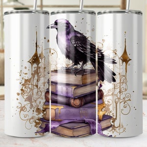 Könnte beinhalten: Ein weißer Edelstahlbecher mit einem violetten Raben, der auf einem Stapel antiker Bücher sitzt. Der Rabe hat einen schwarzen Schnabel und schwarze Augen. Die Bücher sind mit goldenen Akzenten und violetten und goldenen Blumendesigns verziert. Der Hintergrund ist weiß mit goldenen und braunen Spritzern.