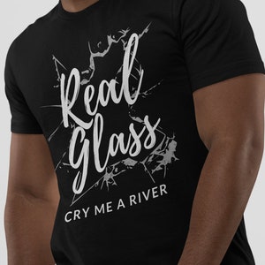 Könnte beinhalten: Schwarzes T-Shirt mit einer weißen Grafik, auf der "Real Glass" mit einem Risseffekt im Glas und dem Text "Cry Me A River" darunter steht.