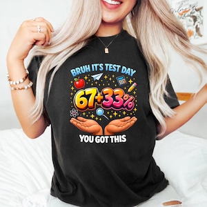 Może przedstawiać: Czarny t-shirt z kolorową grafiką z napisem "Bruh It's Test Day" z ikonami szkolnymi. Grafika zawiera liczby "67+33%" oraz hasło "You Got This".