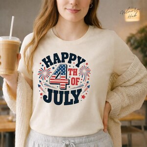 Peut inclure: T-shirt crème avec un motif patriotique "Happy 4th of July". Le graphisme présente un chiffre quatre stylisé avec un motif étoiles et rayures, entouré de feux d'artifice et d'étoiles rouges, blanches et bleues.