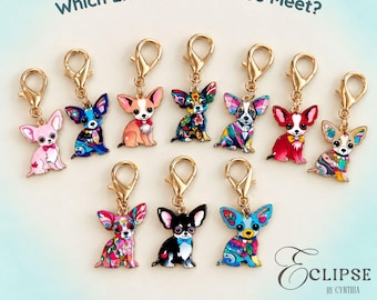May include: A collection of ten metal chihuahua charms with gold-tone lobster clasps. Each charm features a unique colorful graphic design. The text "Which Little Pup Will You Meet?" and "Eclipse by Cynthia" is visible. Includes 1 charm.