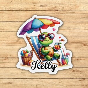 May include: A cartoon turtle wearing sunglasses and a straw hat sits in a beach chair with a tropical drink. The turtle is holding a glass of juice with a straw. The turtle is sitting on a beach with a beach umbrella and a basket of beach balls. The text "Kelly" is written below the turtle.