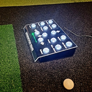 May include: A black and clear plastic golf simulator control panel with white buttons labeled "Select", "Putter", "Haz. Menu", "Option", "CB Menu", "Unlock", "Handicap", "Mulligan", "Tiger", "Finger", "Score", and "SWINGWOOD SIMS".