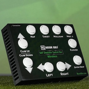 May include: A black golf simulator control box with white buttons labelled "Map", "Target", "Mulligan", "Misc. 1", "Flyover", "Club Up", "Club Down", "Enter/Drop", "Left", and "Right". The box also has a label that says "ROXOR GOLF" and "Golf Simulator Control Box Wireless".