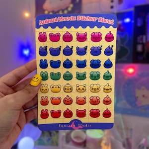 May include: A sticker sheet with a rainbow gradient of animal faces. The sheet is titled "Animal Moods Sticker Sheet" and has a small logo that says "lumicly Studio".
