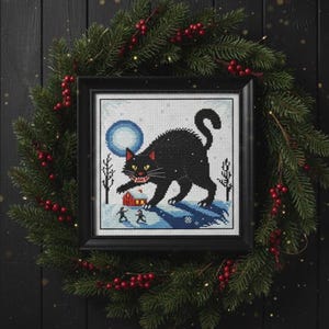Finished Jólakötturinn cross stitch framed and displayed within a dark, Pagan-themed Christmas wreath.