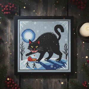 The Yule Cat cross stitch design embroidered on a light grey fabric, highlighting the snowy winter landscape and moonlight.