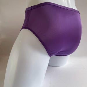 Könnte beinhalten: Lilafarbene Satin-Unterwäsche mit einer glatten, seidenweichen Textur.