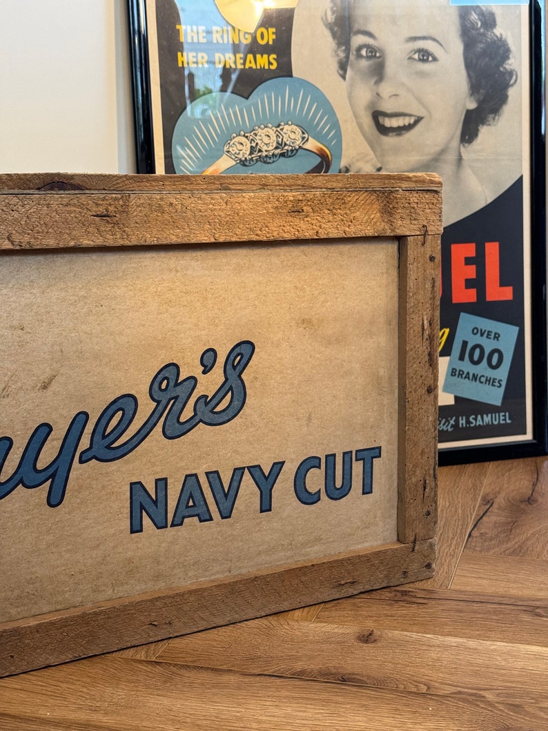 Puede incluir: Un letrero de madera con un logotipo azul y blanco que dice "Ayer's Navy Cut". El letrero est&aacute; enmarcado en un marco de madera r&uacute;stico.