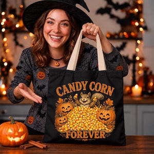 May include: A black canvas tote bag featuring a graphic of a squirrel sitting in a large pile of candy corn, flanked by two jack-o'-lanterns and autumn leaves. The text "CANDY CORN FOREVER" is printed in orange above and below the illustration.