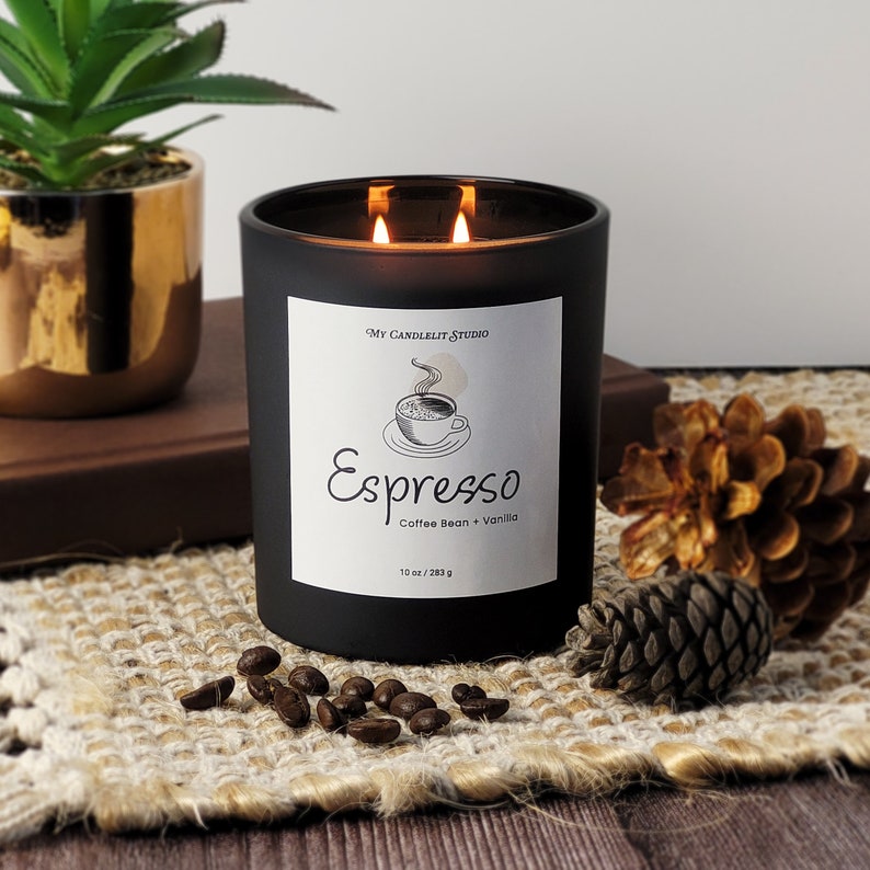 K&ouml;nnte beinhalten: Schwarzes Kerzengef&auml;&szlig; mit einem wei&szlig;en Etikett, auf dem "My Candlelit Studio" und "Espresso Coffee Bean + Vanilla 10 oz / 283 g" steht. Das Etikett zeigt auch eine Zeichnung einer Tasse Kaffee.