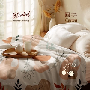 May include: A white blanket with a floral and abstract design in shades of brown, pink, and green. The blanket is draped over a bed with white pillows and a wooden nightstand with a vase of dried flowers.