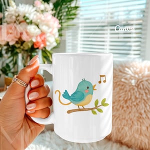 Hand held mug mockup created for Canva featuring a 15oz ceramic mug with a whimsical bird illustration design. Natural lifestyle composition with realistic grip, highlights, and ceramic texture. Mug body is editable via Canva drag and drop and also compatible with PSD smart object. Trendy mugs mockup for creative and playful 15oz mug mockup listings.