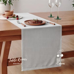 Może przedstawiać: Biały bieżnik stołowy na drewnianym stole z talerzem jedzenia, dwoma kieliszkami do wina i drewnianą miską z wiśniami. Na bieżniku widoczny jest tekst "Table Runner mockup".