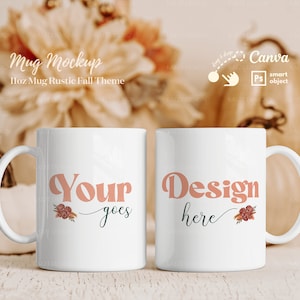 Pode incluir: Duas canecas de cerâmica branca com alças. A caneca à esquerda tem o texto "Your design goes here" em rosa com um design floral. A caneca à direita tem o texto "Design here" em rosa com um design floral. As canecas estão sobre uma superfície de madeira com um fundo desfocado de decoração de outono.