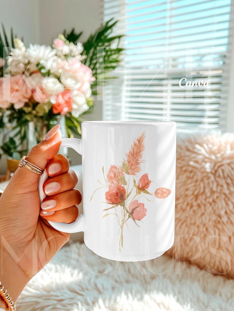 Trendy hand held mug mockup designed for Canva, featuring a 15oz ceramic mug with a delicate botanical illustration example. Styled in a cozy lifestyle setting with natural light and soft textures. Mug body is fully editable using Canva drag and drop while preserving realistic shadows. Ideal mugs mockup for creative sellers and modern mug mockups.